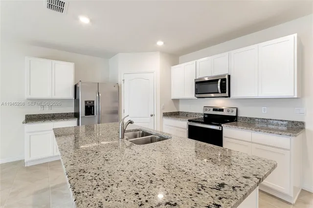 a kitchen with kitchen island granite countertop a sink stove microwave and refrigerator