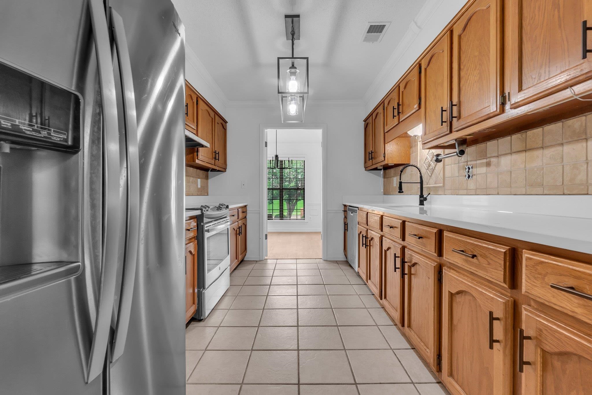 6613 Stephan Ridge Drive Bartlett, TN 38135 - Photo 9 of 24 Galley kitchen featuring wood cabinetry with dark hardware, stainless steel appliances, tile flooring, and light-colored countertops