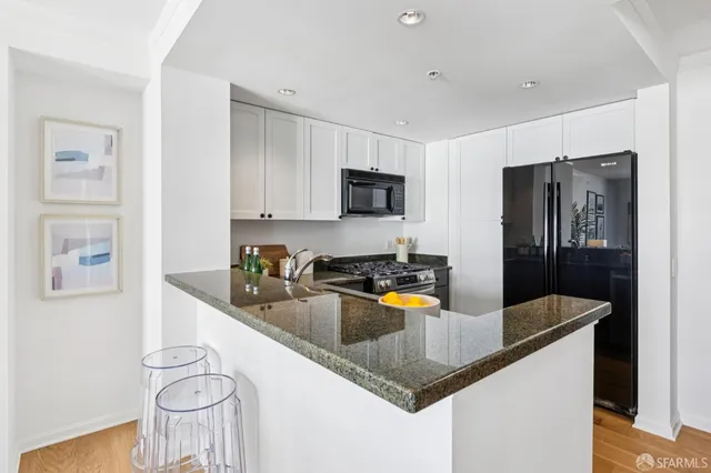 a kitchen with stainless steel appliances granite countertop a refrigerator a stove a sink a refrigerator white cabinets and chairs