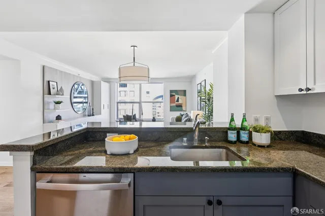 a kitchen with stainless steel appliances granite countertop a sink a stove and white cabinets