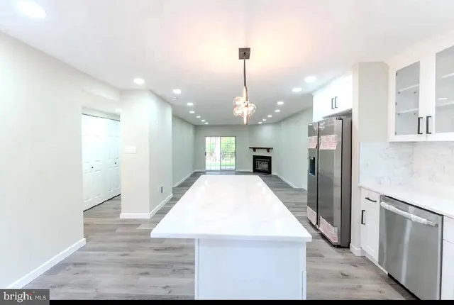 a kitchen with stainless steel appliances kitchen island granite countertop a refrigerator a sink dishwasher a stove and a dining table with wooden floor