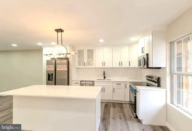 a kitchen with stainless steel appliances granite countertop a refrigerator a sink dishwasher and a oven with wooden floor