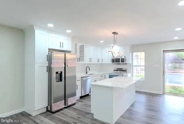 an empty room with wooden floor fireplace and windows