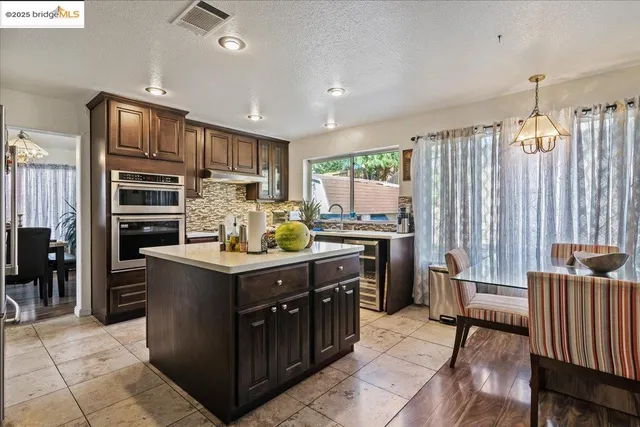 a kitchen with kitchen island granite countertop a stove refrigerator and cabinets