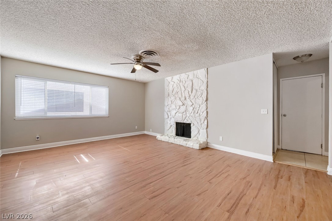 6321 Portola Road Las Vegas, NV 89108 - Photo 8 of 29 Laminate flooring throughout highlights the stone fireplace in this open living space.