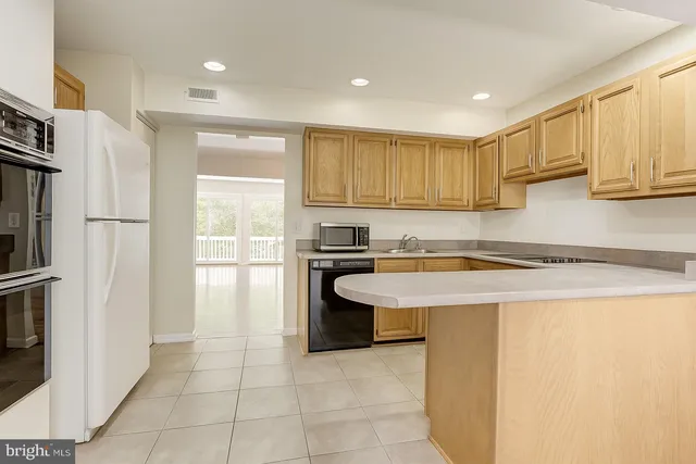 a kitchen with stainless steel appliances granite countertop a refrigerator a sink and white cabinets