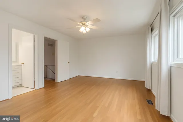 a view of empty room with wooden floor and fan