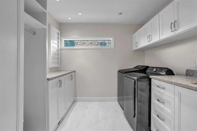 a utility room with cabinets washer and dryer