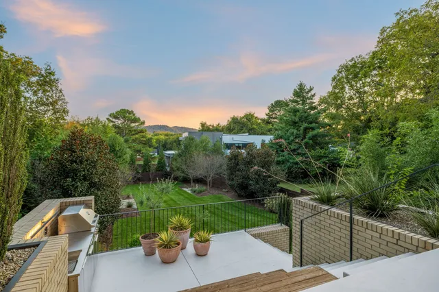 a view of a table and chairs and potted plants with large trees