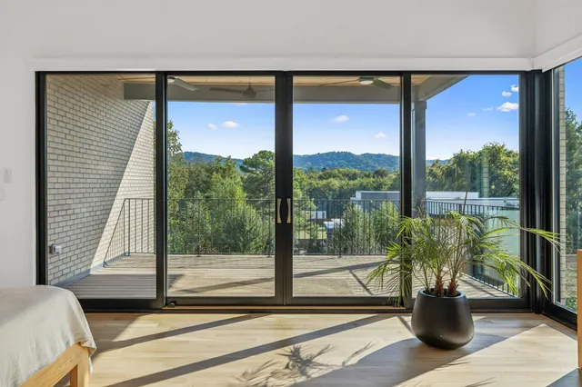 a view of a living room with a floor to ceiling window and wooden floor