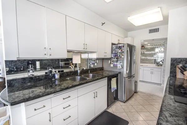 a kitchen with stainless steel appliances granite countertop a refrigerator a stove and white cabinets