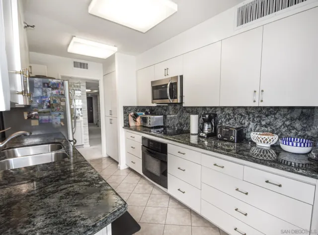 a kitchen with granite countertop a sink stainless steel appliances and cabinets
