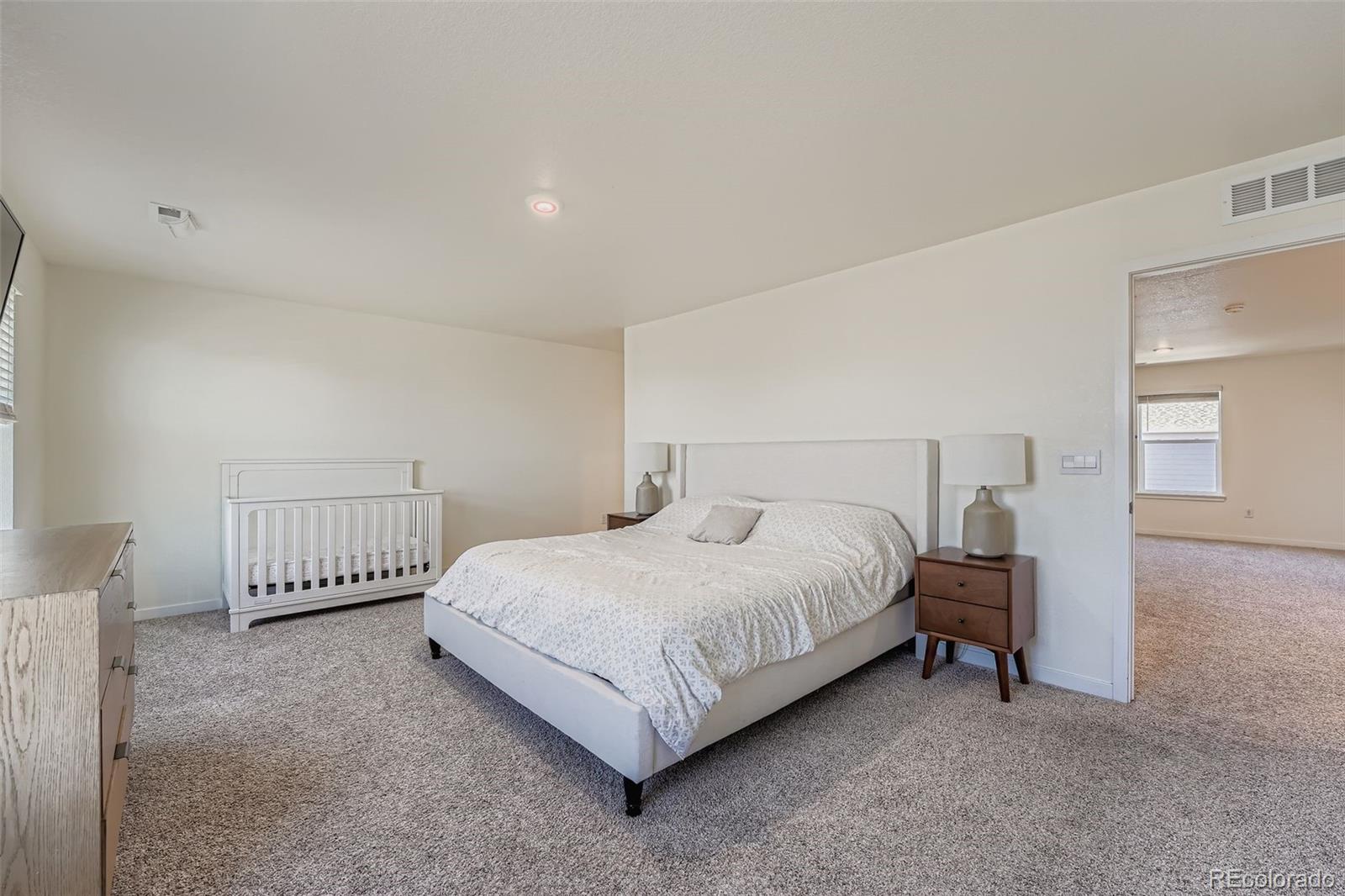 195 Yellowtail Street Bennett, CO 80102 - Photo 14 of 31 a bedroom with a bed and a lamp