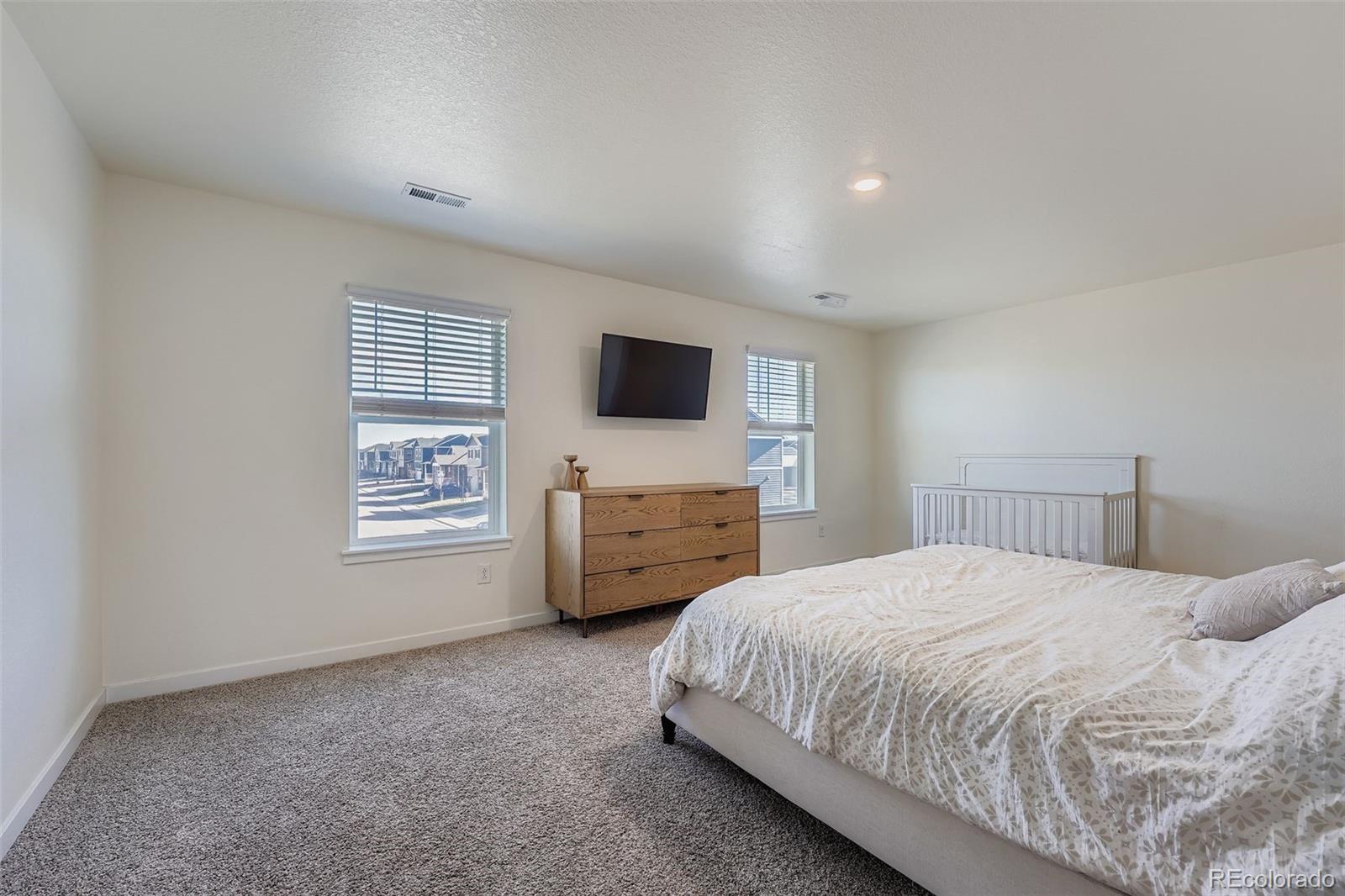 195 Yellowtail Street Bennett, CO 80102 - Photo 15 of 31 a bedroom with a bed a tv and dresser