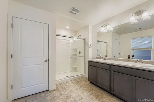 a bathroom with a double vanity sink mirror and shower