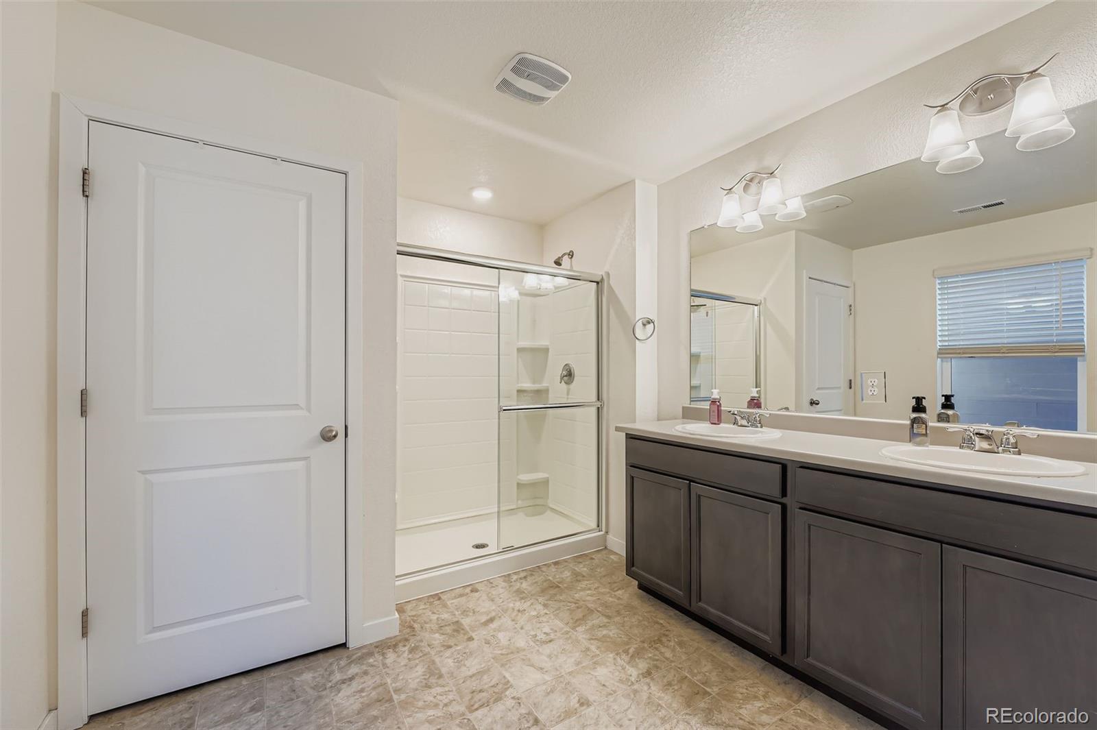 195 Yellowtail Street Bennett, CO 80102 - Photo 16 of 31 a bathroom with a double vanity sink mirror and shower