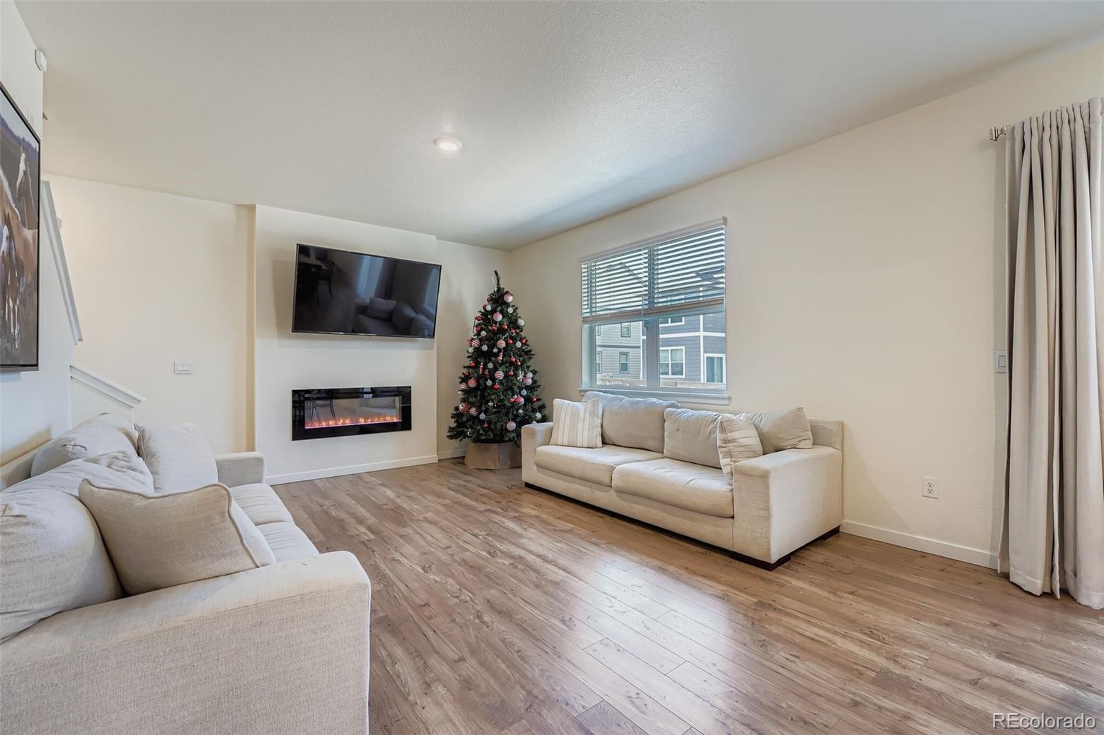 195 Yellowtail Street Bennett, CO 80102 - Photo 6 of 31 a living room with furniture a flat screen tv and a fireplace