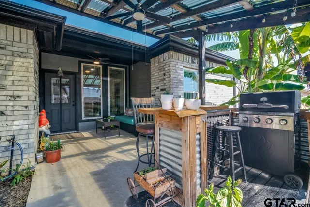 a view of a patio with table and chairs potted plants and floor to ceiling window