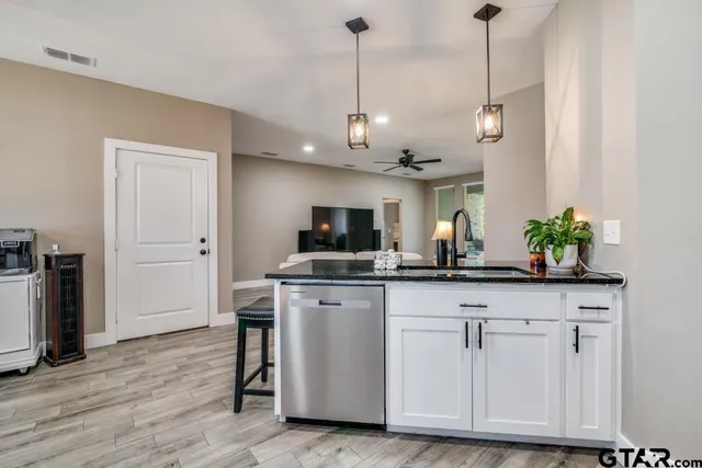 a view of a kitchen with stainless steel appliances granite countertop a sink a refrigerator a counter space and wooden floor