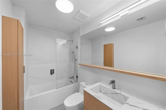 a bathroom with a granite countertop sink mirror toilet and bathtub