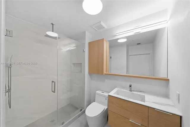 a bathroom with a toilet a sink a mirror a shower and vanity