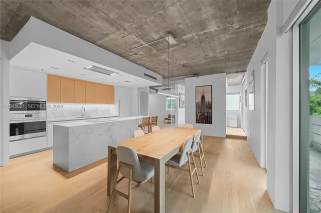 a kitchen with stainless steel appliances kitchen island granite countertop a table chairs and a refrigerator