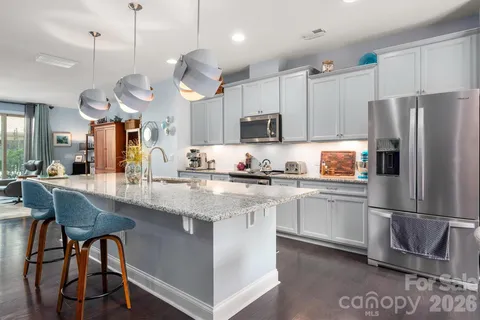 a kitchen with stainless steel appliances granite countertop a sink a stove a refrigerator and island