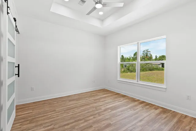 an empty room with wooden floor and windows