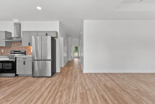 a kitchen with a refrigerator a stove and a wooden floor