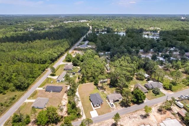 an aerial view of residential house with outdoor space and trees all around