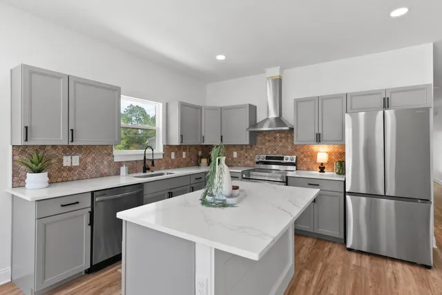 a kitchen with a refrigerator a sink dishwasher a stove and white cabinets with wooden floor