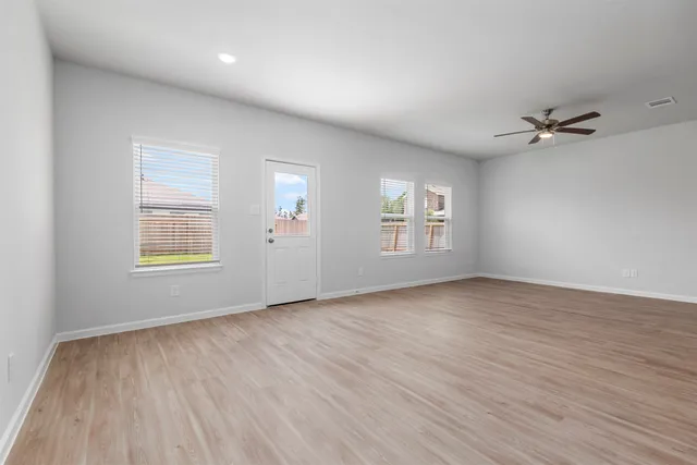a view of an empty room with a window and wooden floor