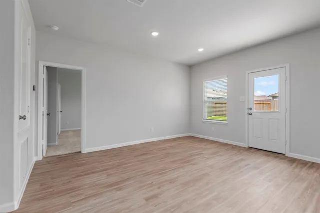 a view of an empty room with wooden floor and a window