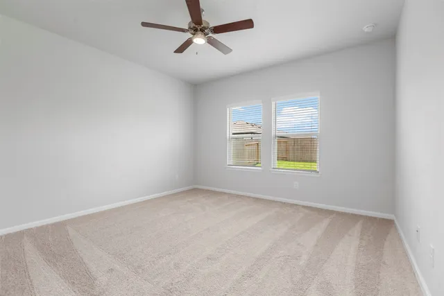 an empty room with windows and ceiling fan