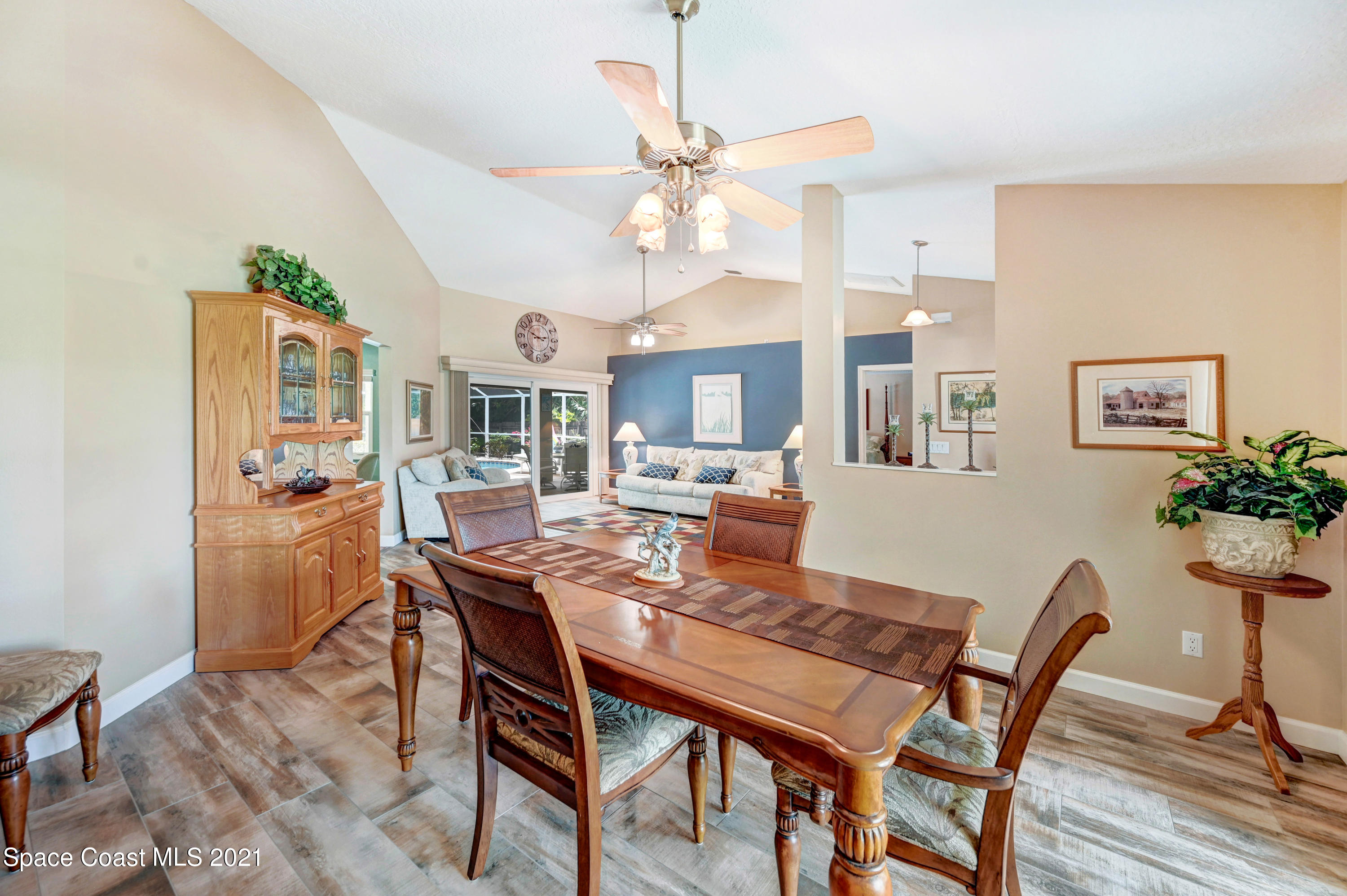 4689 Canard Road Melbourne, FL 32934 - Photo 9 of 49 a dining room with wooden floor a chandelier fan a wooden table and chairs