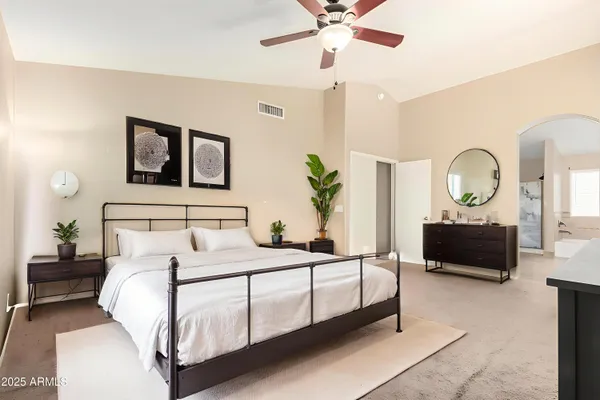 a bedroom with a bed a mirror and paintings on the wall