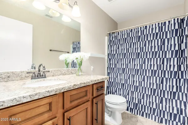 a bathroom with a granite countertop sink vanity mirror and toilet