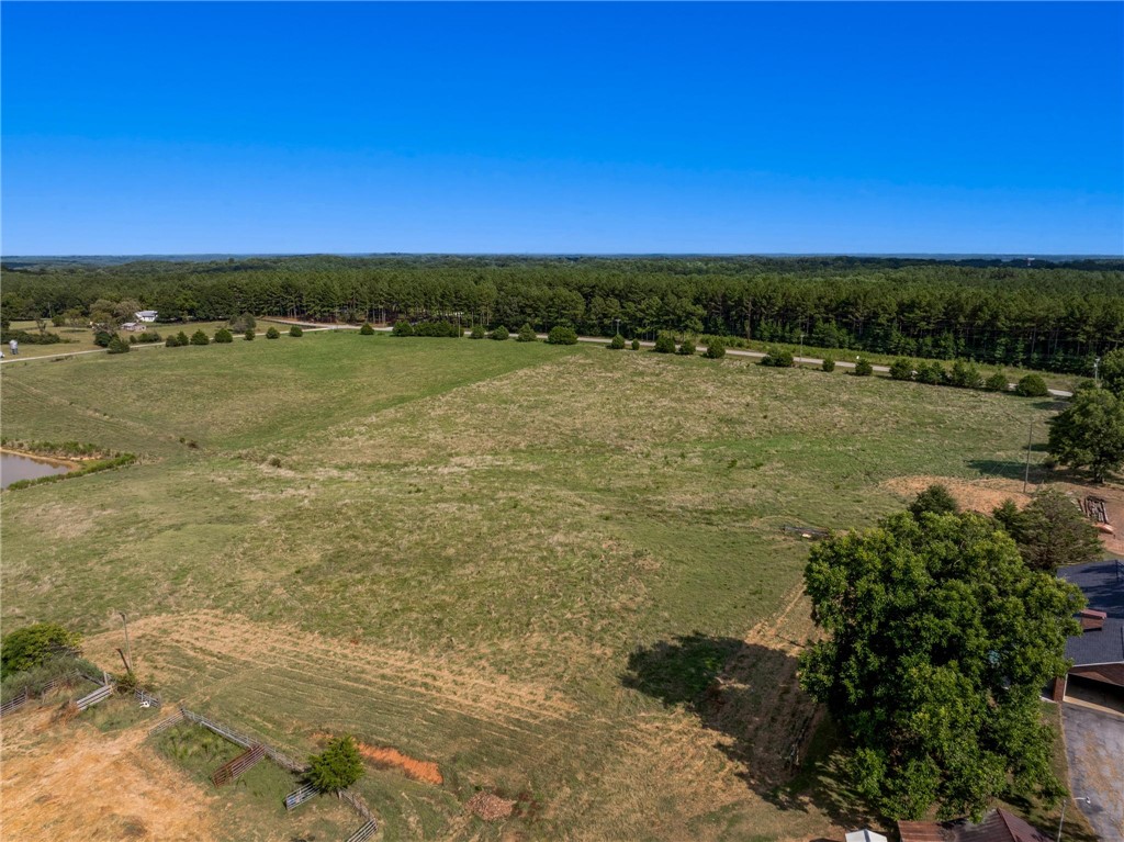 910 Highway 182 Fair Play, SC 29643 - Photo 44 of 50 An aerial perspective showcases vast green pastures bordered by dense treelines under clear blue skies.