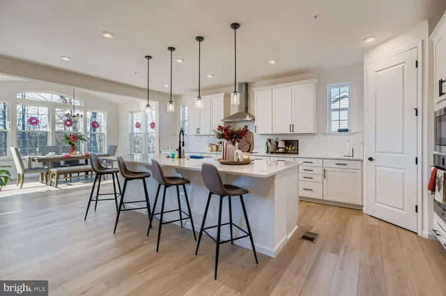 a kitchen with white cabinets sink dining table and chairs