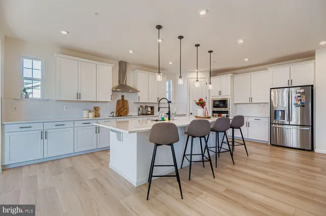 a kitchen with stainless steel appliances granite countertop a table chairs stove a sink dishwasher a refrigerator and cabinets with wooden floor