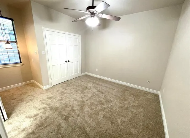 en empty room with windows and ceiling fan
