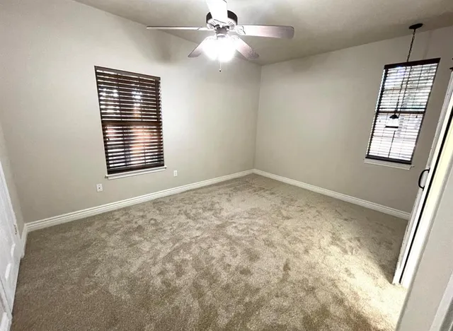 en empty room with windows and ceiling fan