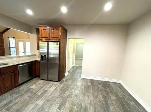 a large kitchen with granite countertop a refrigerator and a sink