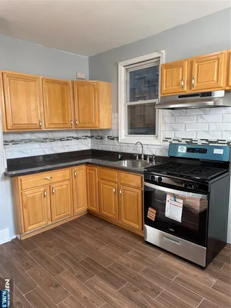 a kitchen with stainless steel appliances granite countertop wooden cabinets stove top oven and sink