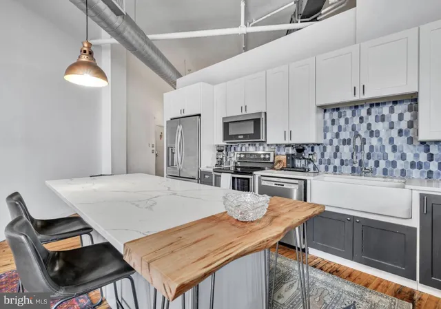 a kitchen with stainless steel appliances kitchen island granite countertop a table chairs sink and cabinets