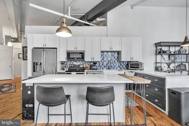 a kitchen with stainless steel appliances granite countertop a sink a stove a refrigerator cabinets and chairs