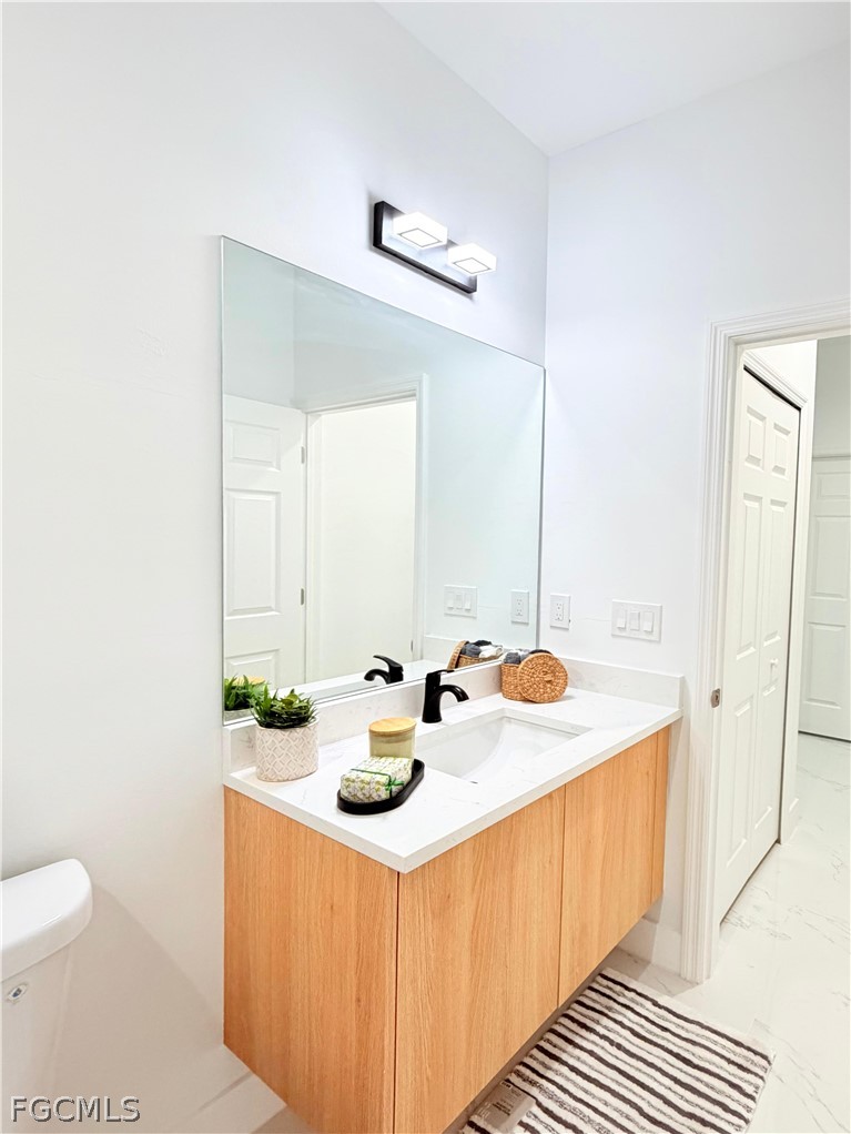 767 Crystal Avenue Lehigh Acres, FL 33974 - Photo 6 of 17 a bathroom with a sink a toilet and vanity