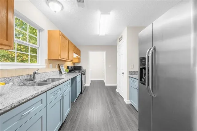 a kitchen with stainless steel appliances granite countertop a refrigerator a sink a stove and a wooden floors