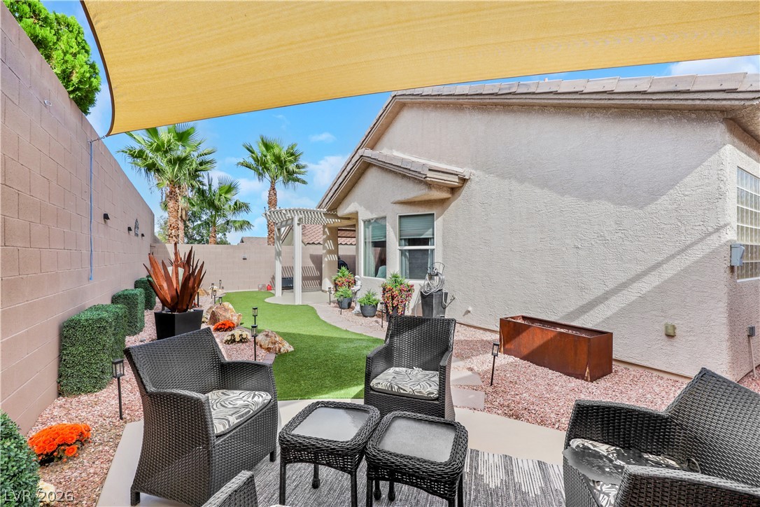 2635 Dirleton Place Henderson, NV 89044 - Photo 46 of 50 A shaded patio terrace overlooks a manicured lawn area framed by stone walls.