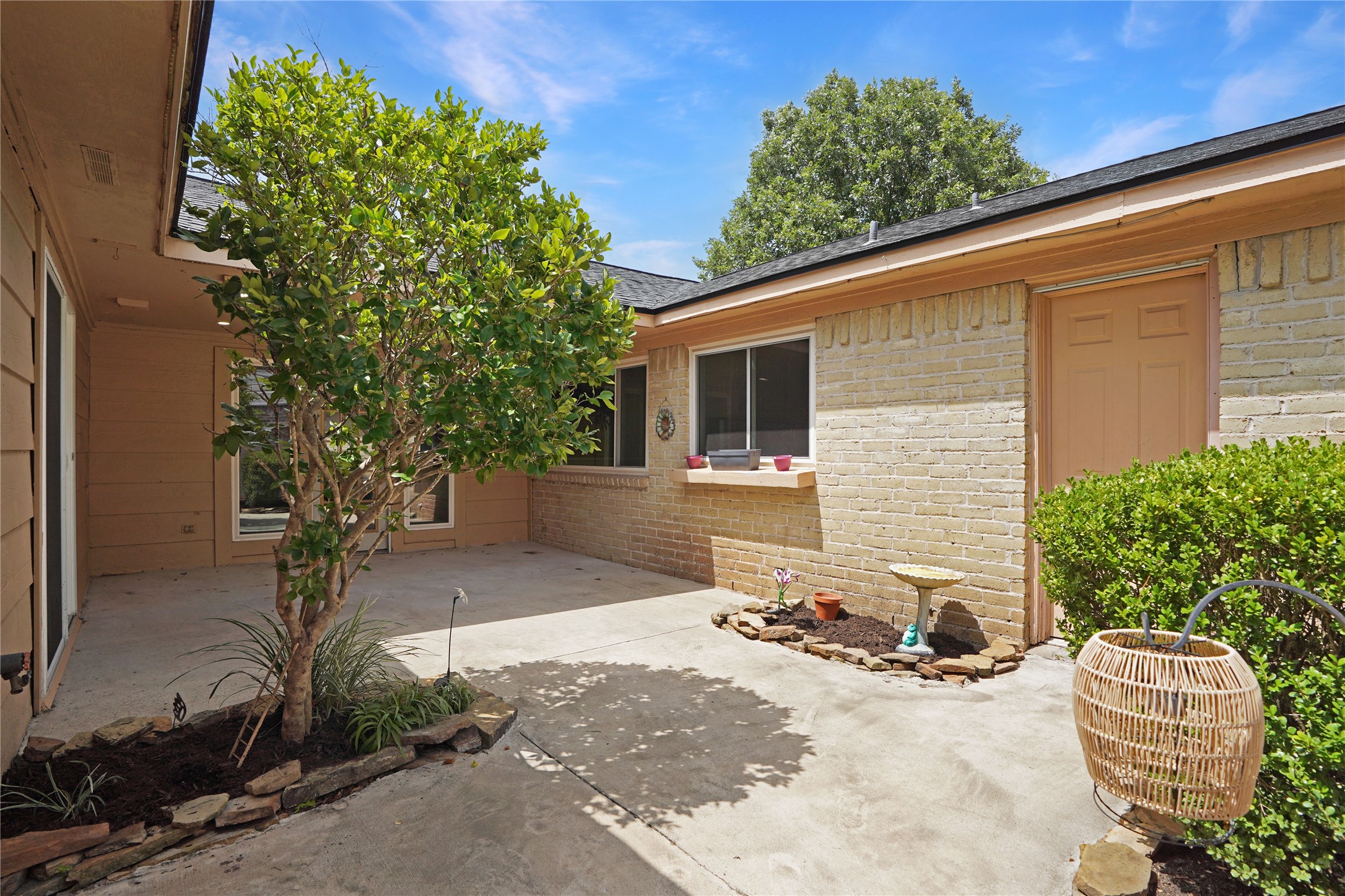 17119 Mellow Ridge Drive Spring, TX 77379 - Photo 26 of 32 This photo showcases a charming courtyard with a concrete patio, surrounded by brick and siding walls. It features a small garden area with a tree and plants, offering a cozy outdoor space for relaxation or entertaining.